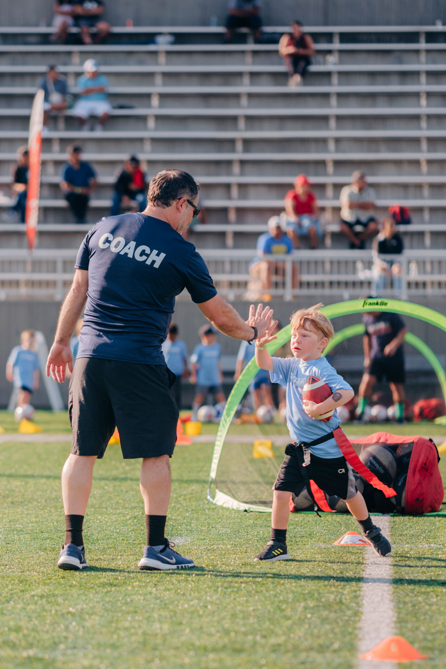 Skyhawks football coach and player share a high-five in Minnesota, symbolizing the power of encouragement and growth in youth sports.